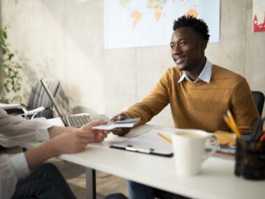 Person receiving a passport with a world map background for visa sponsorship jobs guide