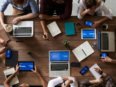 Team meeting with laptops and tablets showing visa sponsorship jobs opportunities in 2025