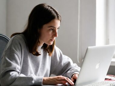 Young woman working remotely from home on her MacBook, enjoying one of the best high-paying remote jobs for beginners in 2025