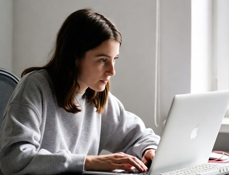 Young woman working remotely from home on her MacBook, enjoying one of the best high-paying remote jobs for beginners in 2025