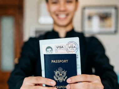 Happy African student proudly holding open passport with approved US student visa stamp, celebrating study abroad success 2025
