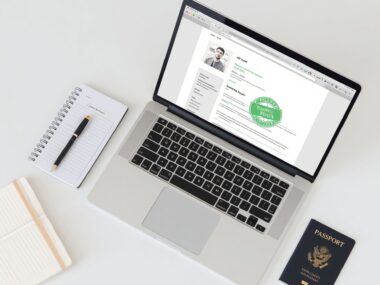 A professional laptop displaying an international resume template alongside a passport and an airline boarding pass on a clean desk.